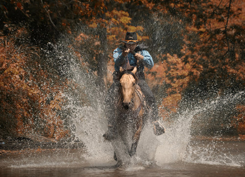 A vintage action shot of a cowboy riding a horse, wading through the water and holding a rifle, Texas 1000pc Puzzle